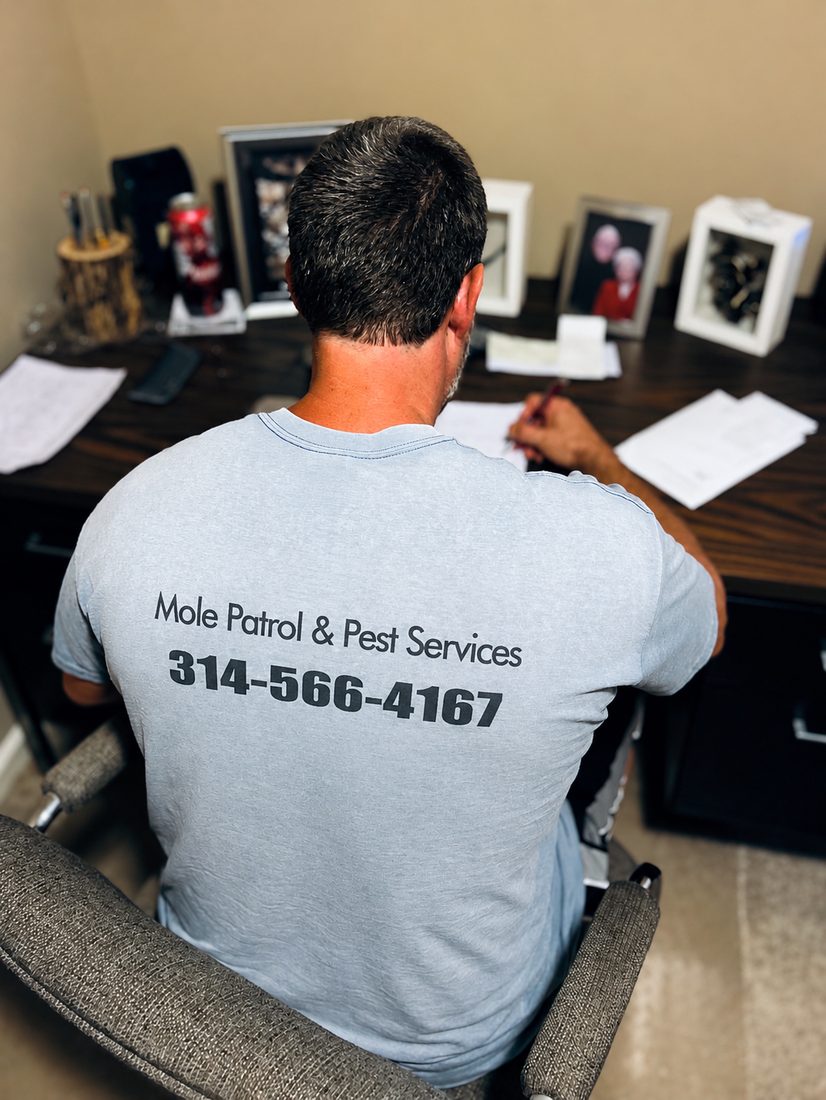 Curt at his desk in a Mole Patrol & Pest Services shirt